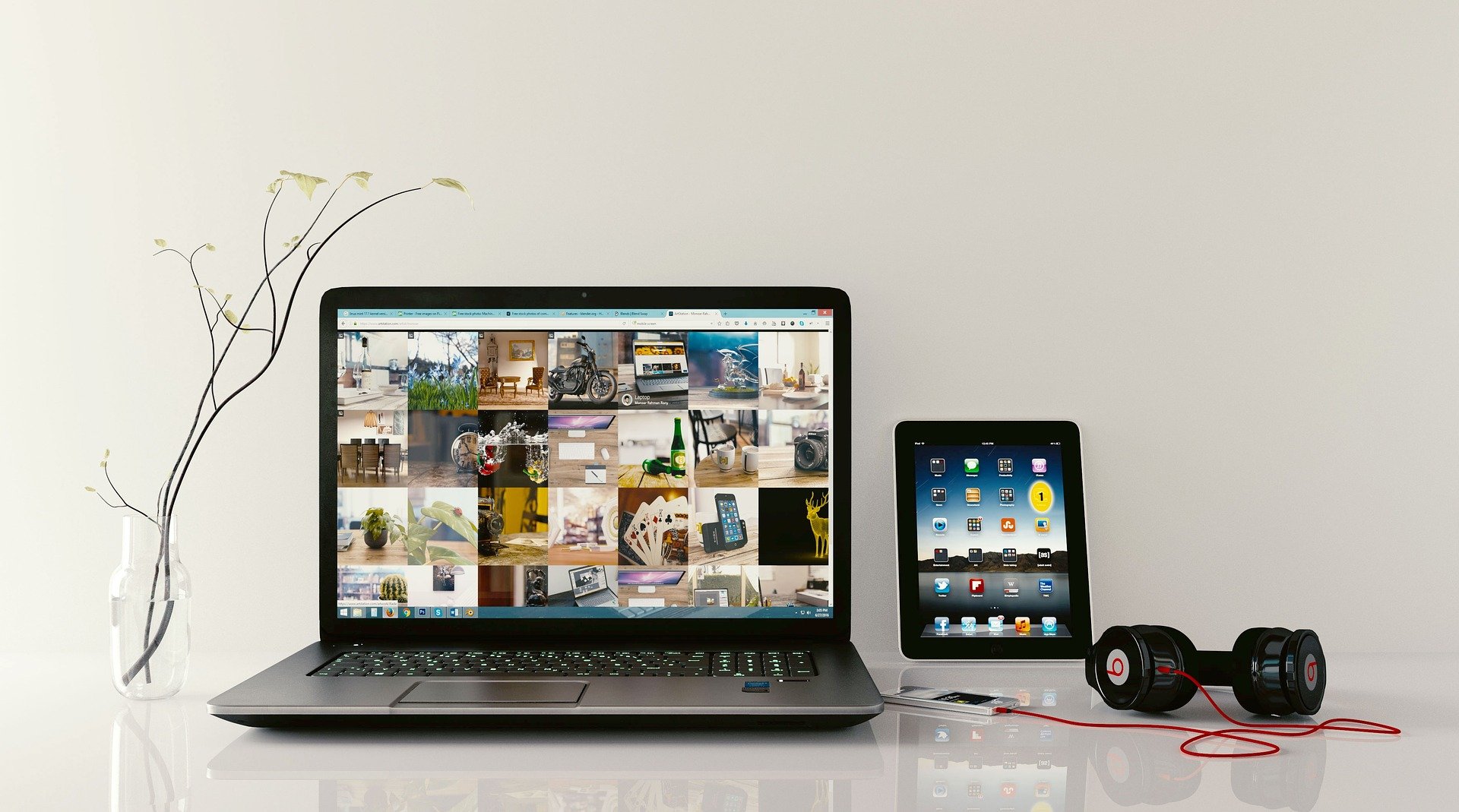 Laptop pozyskany za pomocą wynajmu laptopa. Na stole widać również tablet, słuchawki i wazon.